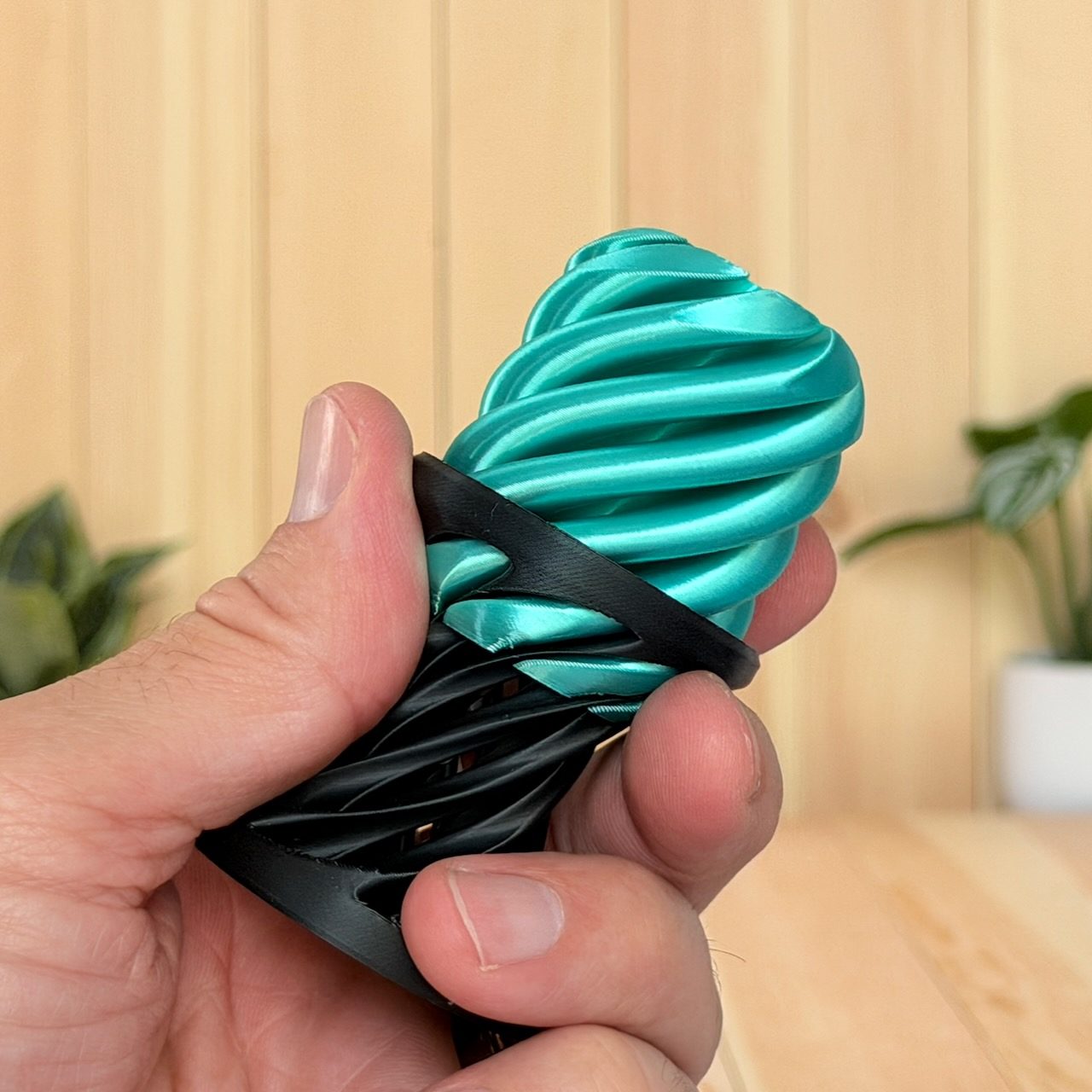 Hand squeezing a teal spiral flexy fidget toy showing the spring compression