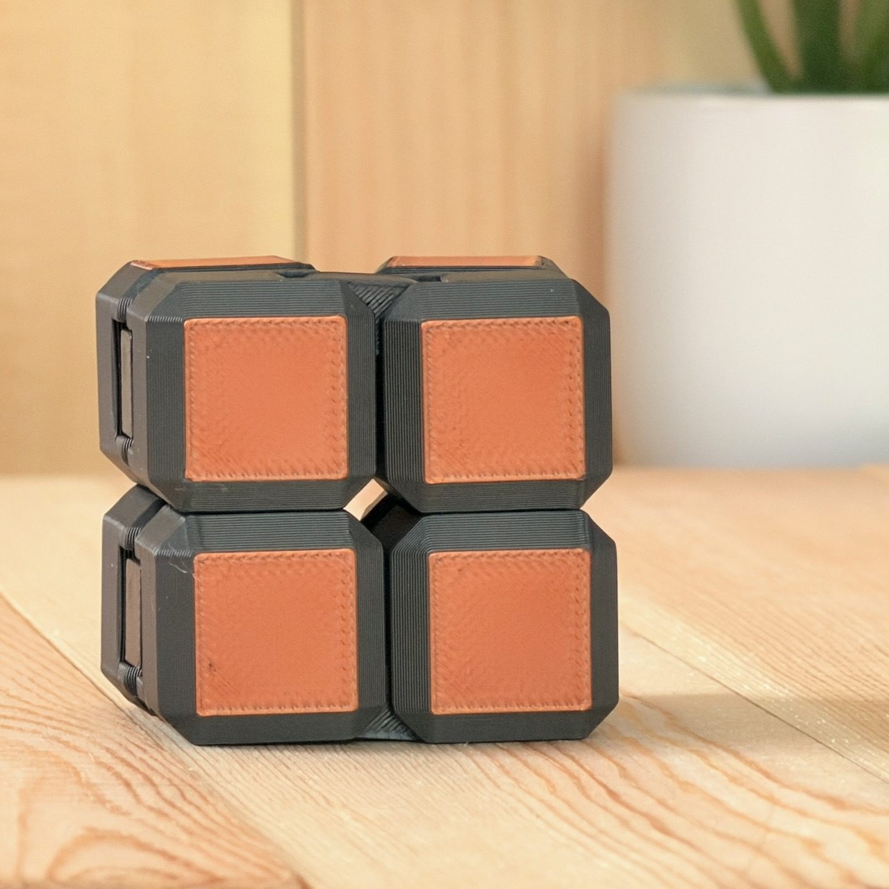 Orange and black infinity folding fidget cube on a wood surface