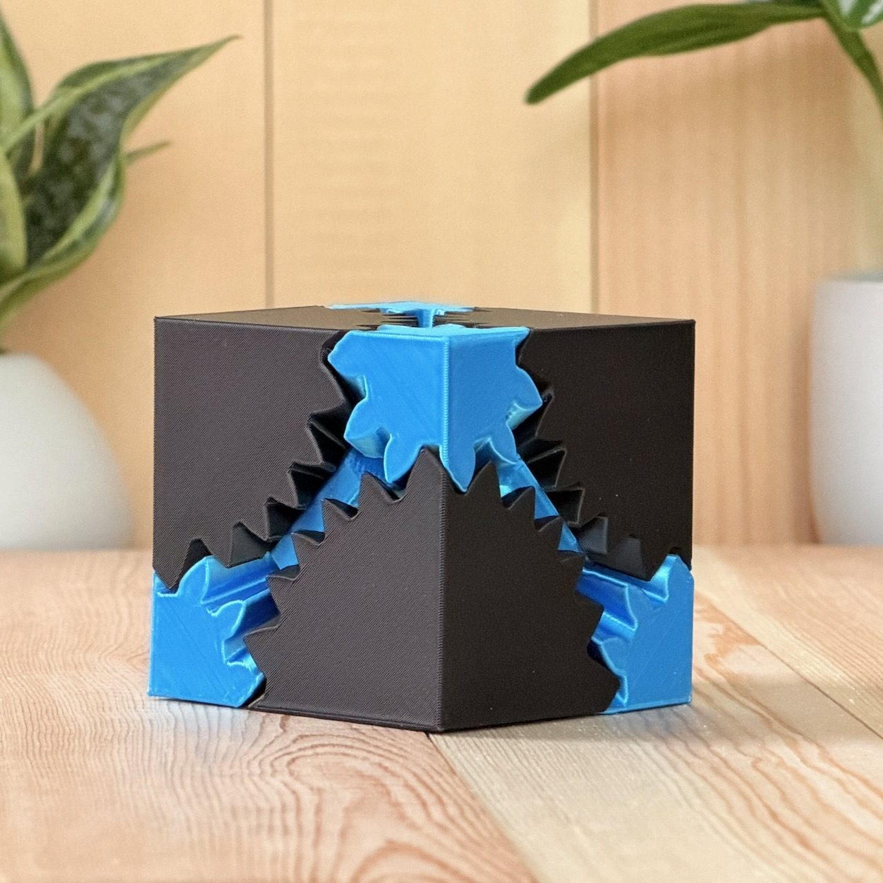 Black fidget cube with bright blue rotating gears on each face
