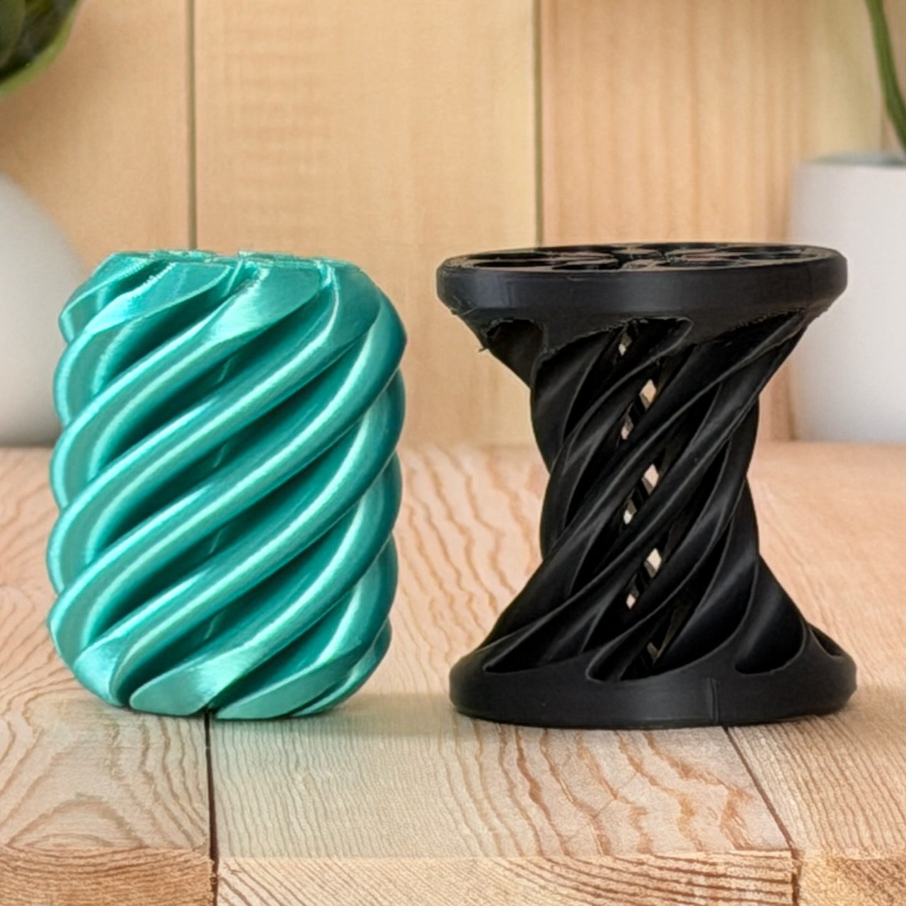 Teal twisted spool fidget next to a black spiral hourglass spool