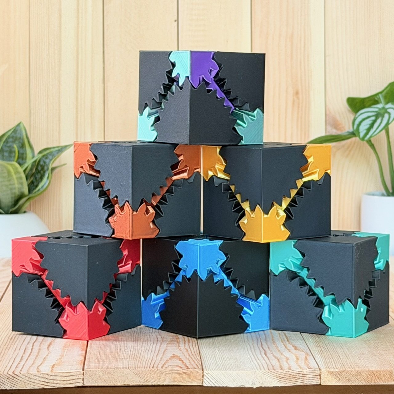 Pyramid stack of black gear cubes with multicolored gears